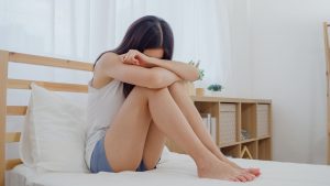 Asian woman depression feeling sad lying on bed in bedroom.