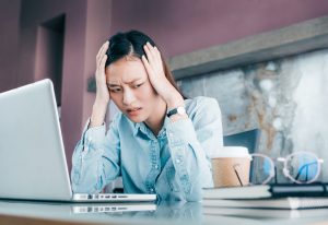 Stressed Asian businesswoman cover her face with hand and feel depression