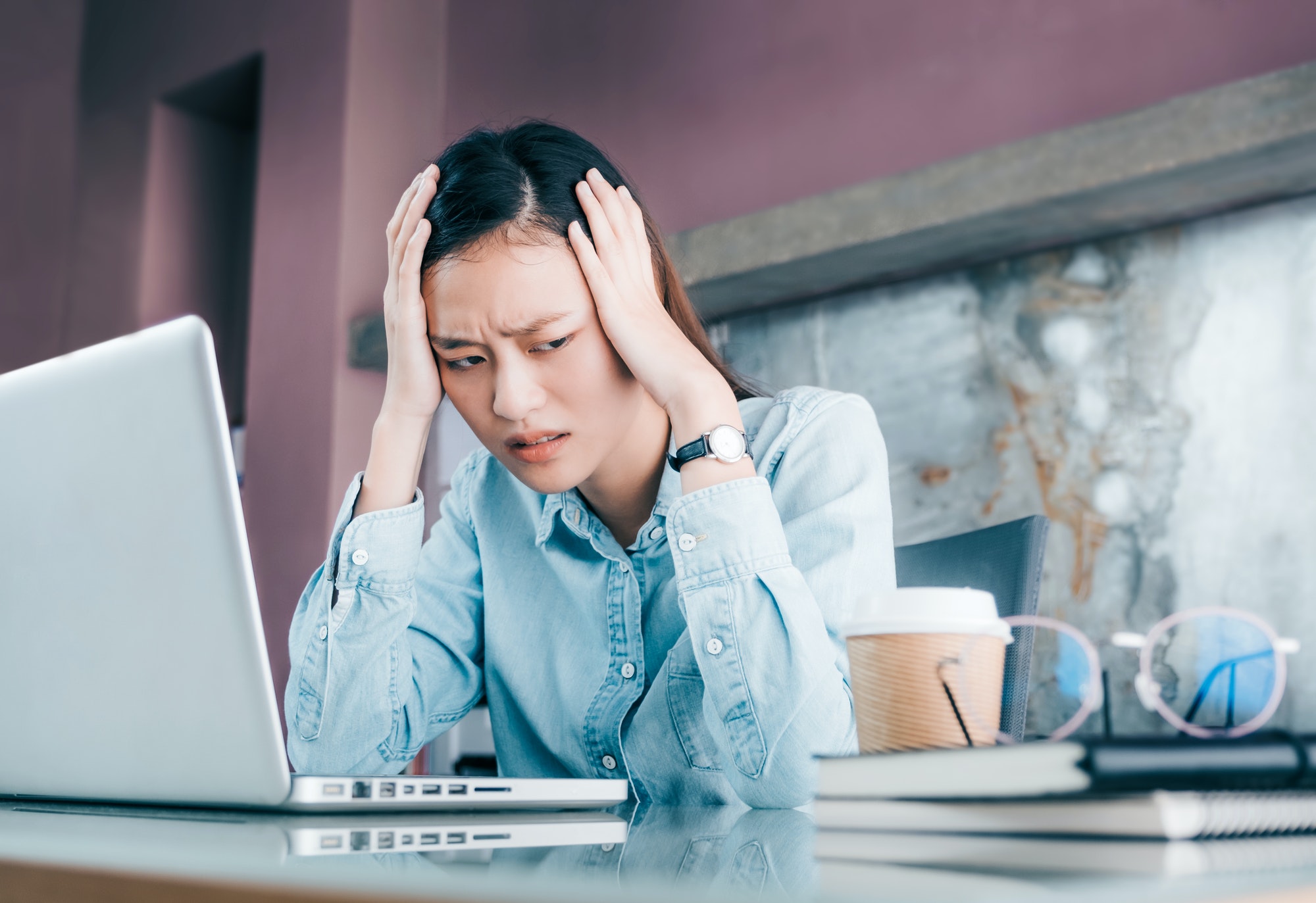 Stressed Asian businesswoman cover her face with hand and feel depression